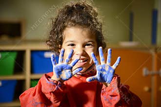 Little girl painting with hands in kindergarten