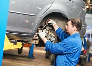 Auto mechanic at car suspension repair work