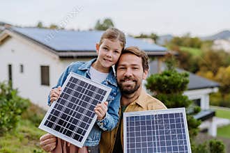Father with his little daughter near their house with solar panels. Alternative energy, saving resources and sustainable