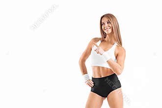 Isolated fit girl pointing at the white wall with copy space. Athlete woman. Muscular young fitness female.
