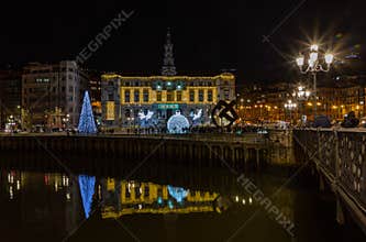 Christmas lights decorate the facade and exterior of the Bilbao City Hall, and are reflected in the river. Basque Country.