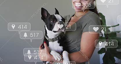On smiling down, woman holding terrier, social media icons floating and updating engagement metrics