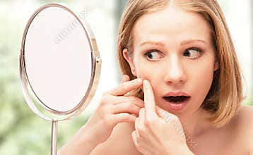 Beautiful healthy woman frightened saw in the mirror acne and w
