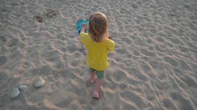 Child holding blue flip flops