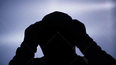 robbery and theft concept, adult man in black balaclava putting hood on head in backlight
