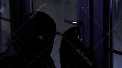 robbery and crime, a man in a balaclava uses master keys to open a door to get into someone else's apartment