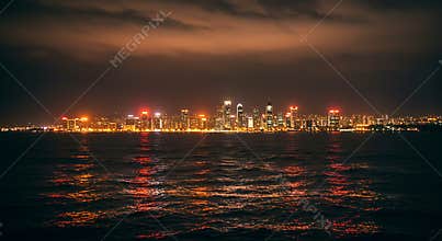 City Skyline Reflecting in Water at Night with Dramatic Moody Sky