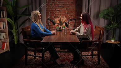 Two Influencers of women being interviewed in a loft-style podcast studio