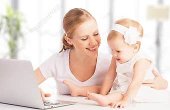 Mother and baby at home using laptop computer