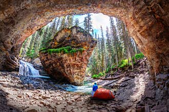 Lone camper at Hidden Cave in Johnston Canyon, Banff National Park, with waterfall and limestone bedrock