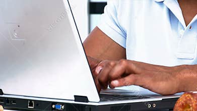 Closeup of a man working on the laptop while having breakfast