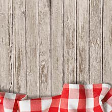 Old wooden table background with picnic tablecloth