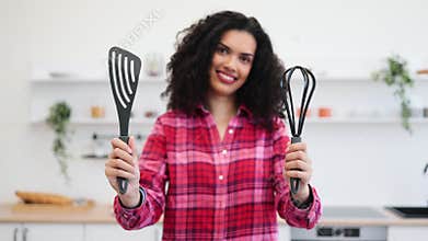 Smiling African Woman Holding Kitchen Utensils in Modern Home Kitchen