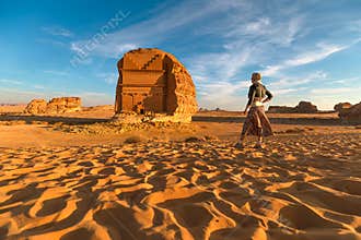Tourist walking in the desert admiring Qasr Al Farid, the tomb of Lihyan son of Kuza in Hegra, Al Ula, Saudi Arabia