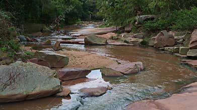 A river winds lazily between boulders in a subtropical river valley.