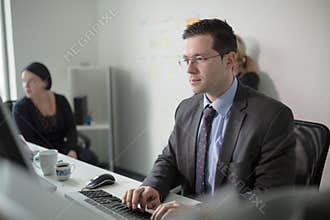 Serious devoted business man work in office on computer. Real economist business people, not models. Bank employees discussing