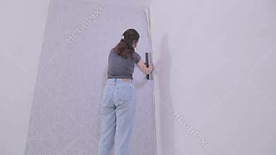 Trimming wallpaper in the corners of a room after wallpapering. Trimming excess paper.