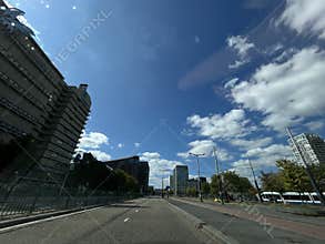 Empty city street beneath bright blue sky with scattered clouds, modern