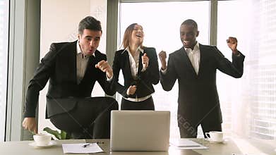 Three excited business people dancing in the workplace, celebrating victory