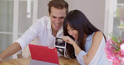 Happy couple showing off ultrasound pictures