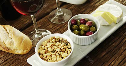 Bowl of peanuts, olives and cheese served with red wine