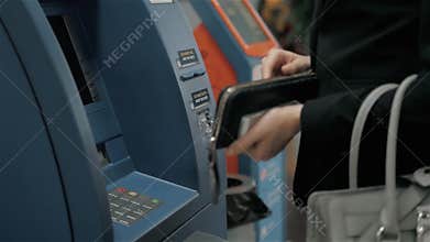 Young woman inserting a credit card to ATM, beautiful girl banking, business woman after work in bank, shopping mall