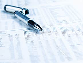 Financial business pen on currencies newspaper