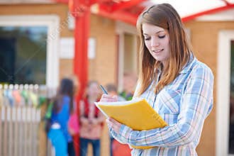School Teacher Making Notes In Playground