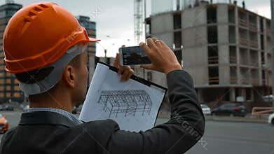 Engineer with the smart phone taking pictures of construction