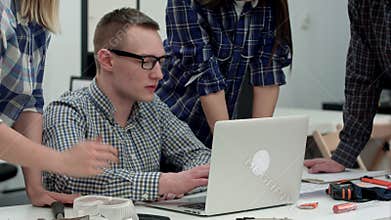 Serious manager in glasses looking at computer and talking to his team