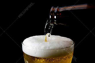 Beer is pouring into glass on black