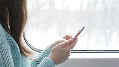 Young girl traveling in a train and using mobile phone. Beautiful woman sends a message from the smartphone. Female