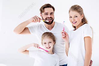 Family cleaning teeth with toothbrushes together on white