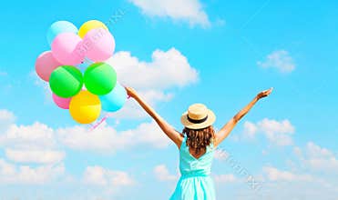 Back view happy woman with an air colorful balloons is enjoying a summer day on blue sky background
