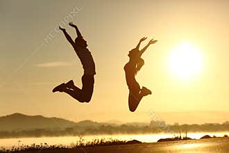 Fitness couple jumping happy at sunset