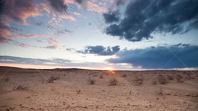 Clouds float over the desert at sunset.