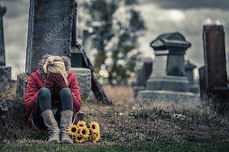 Lonely Sad Young Woman in Mourning in front of a Gravestone