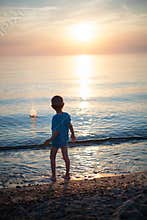 Child boy on beach sunset backlight