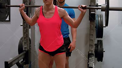 Trainer spotting woman lifting weight