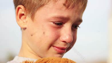 Dirty orphan boy close-up crying and petting a