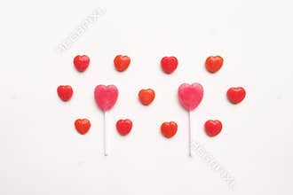 Pink Valentine`s day heart shape lollipop small red candy in cute pattern on empty white paper background. love concept. top view.