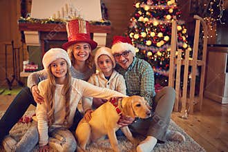 Family and dog sitting by xmas tree