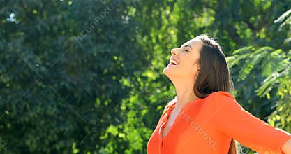 Woman in orange breathing fresh air in a park