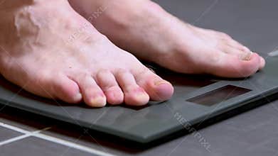 Male feet on glass scales, men`s diet, body weight