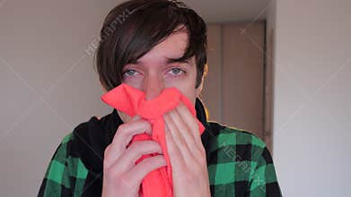 Healthcare, flu, hygiene and people concept - sick man coughing and blowing nose to paper napkin at home