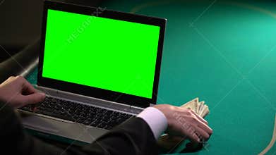 Man using laptop on poker table, earning money in online betting, gambling