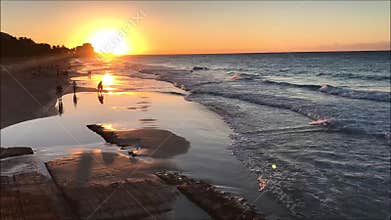 Time lapse video clip of tropical sandy beach with people during sunset