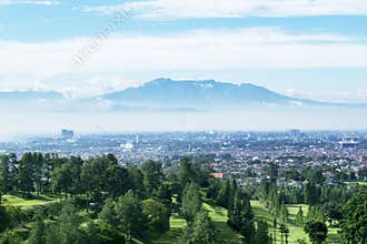 Golf course with misty Bandung cityscape background