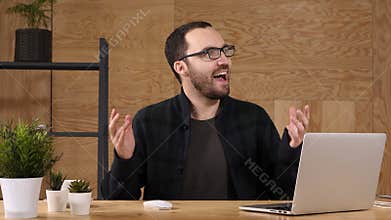 Happy young businessman ilooking at laptop excited by good news, win, victory.