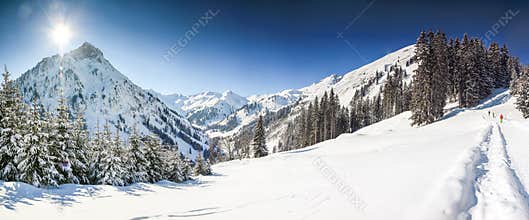 Three people hiking in mountains winter landscape with deep snow on clear sunny day. Allgau, Bavaria, Germany.